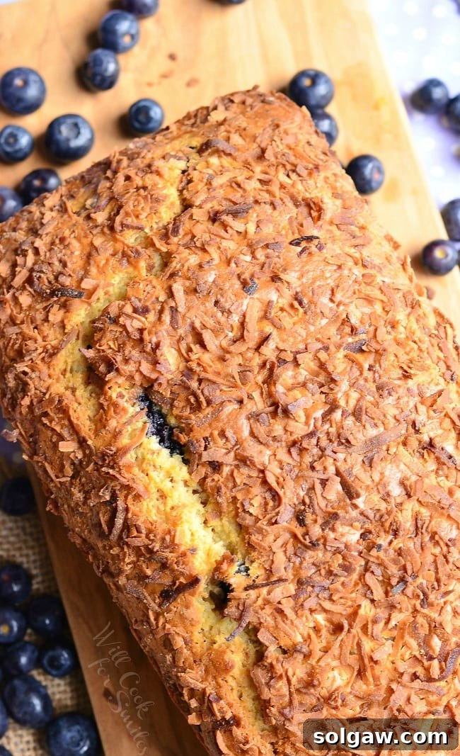 Close-up of Coconut Blueberry Bread slices on a cutting board with blueberries around it
