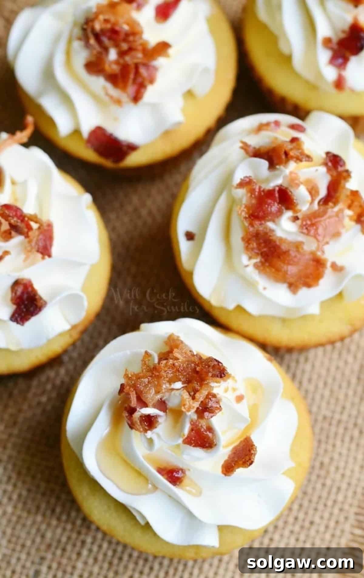 An array of elegantly arranged maple bacon cupcakes, topped with fluffy buttercream, golden maple syrup, and crispy bacon bits, ready to be enjoyed.