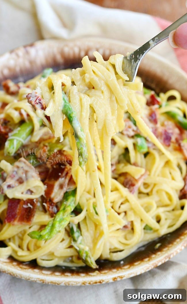 Bacon Asparagus Pasta Carbonara on a plate with a fork with pasta on it