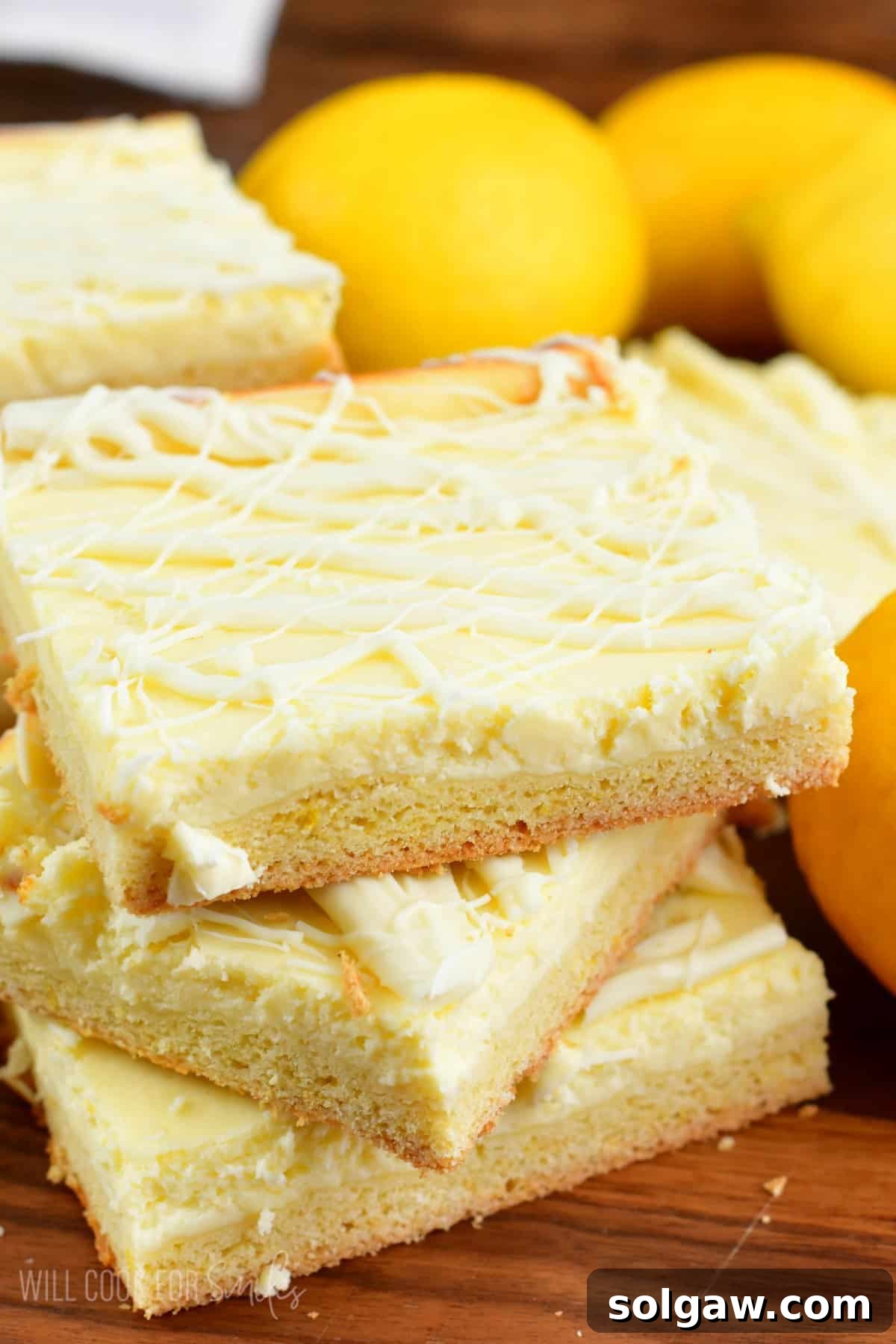 A stack of golden-brown lemon cheesecake cookie bars on a wooden cutting board, showcasing their thick, creamy lemon layer and sturdy cookie base.