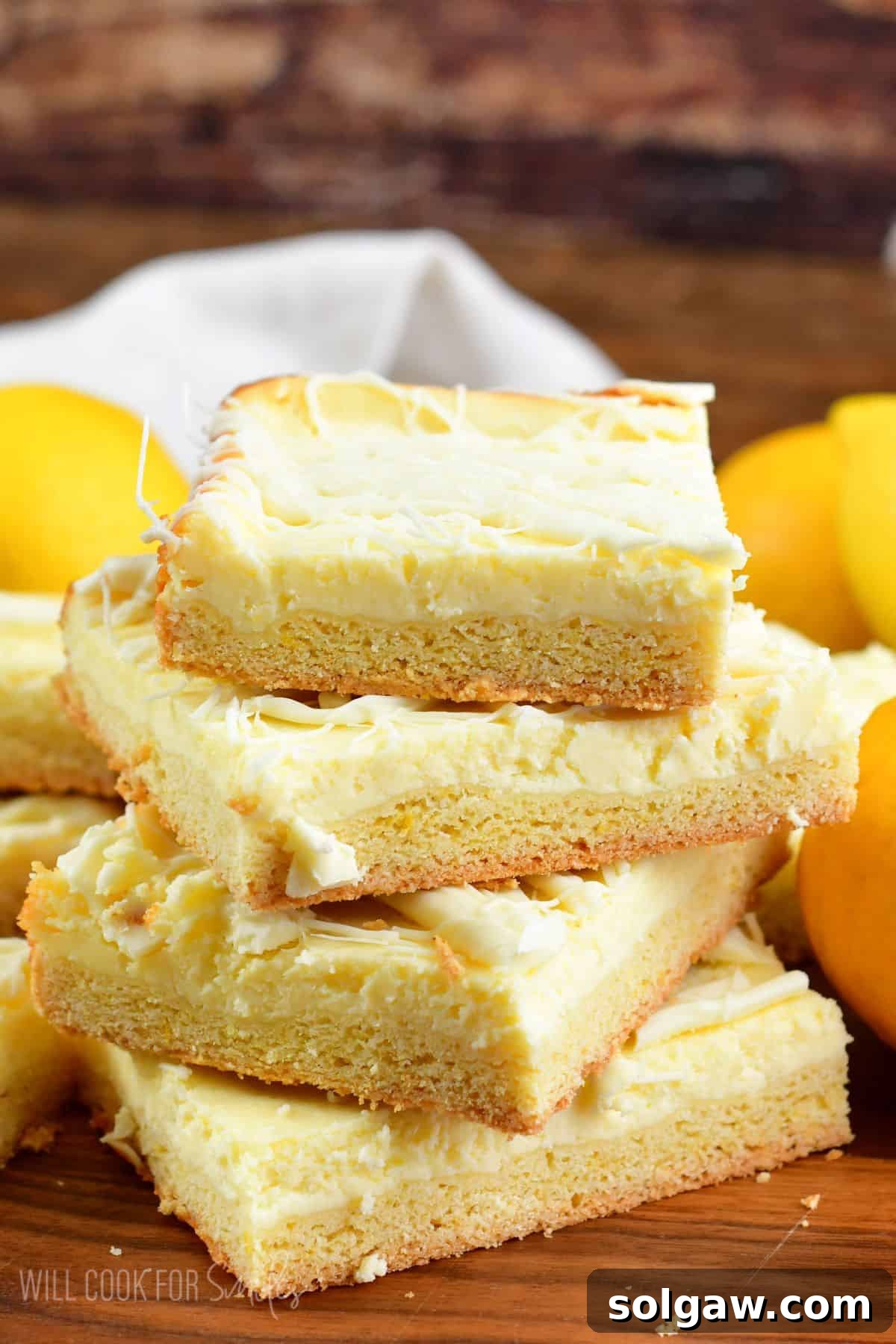 Stacked lemon cheesecake cookie bars, showcasing their distinct cookie and cheesecake layers, ready for a delicious treat.
