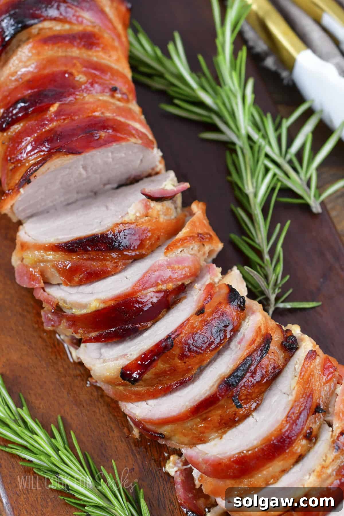 Bacon Wrapped Pork Perfection 11 Top view of beautifully sliced Bacon Wrapped Pork Tenderloin on a serving platter.