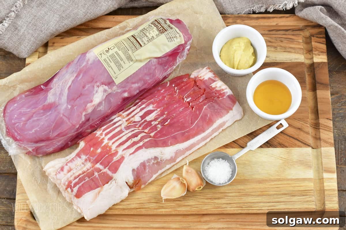 Bacon Wrapped Pork Perfection 3 Ingredients laid out for Bacon Wrapped Pork Tenderloin: pork tenderloin, bacon, Dijon mustard, garlic, honey, and salt.