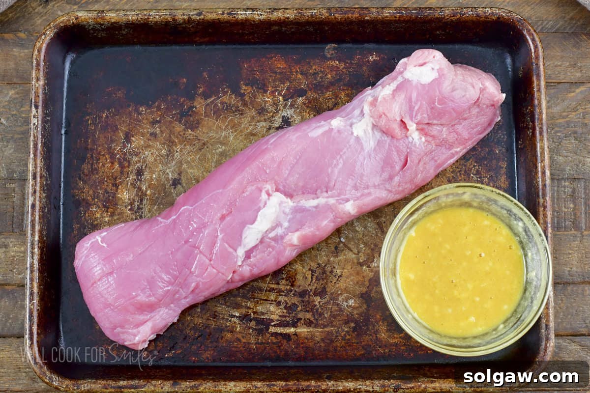 Bacon Wrapped Pork Perfection 4 Pork tenderloin resting next to a bowl of Dijon mustard and honey sauce.