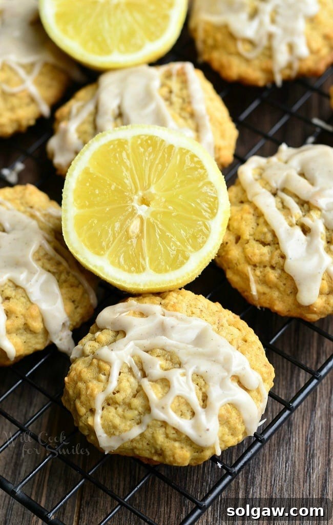 Lemon vanilla glazed oatmeal cookies with a whole lemon in the center, arranged on a cooling rack.
