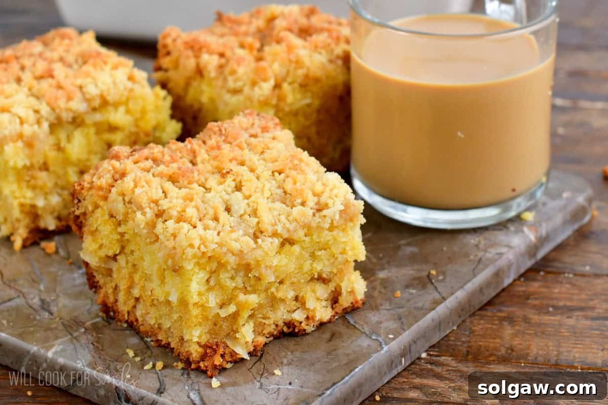 three slices of coconut coffee cake with a glass mug of coffee on a piece of marble.