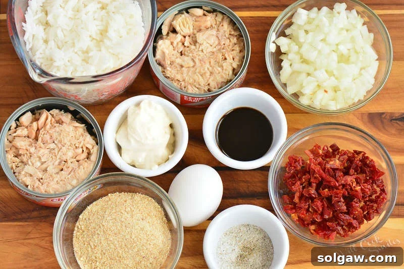 Savory Salmon and Rice Cakes 3 A selection of fresh ingredients laid out on a cutting board, including diced onions, sun-dried tomatoes, canned salmon, and cooked rice, ready for making salmon and rice patties.