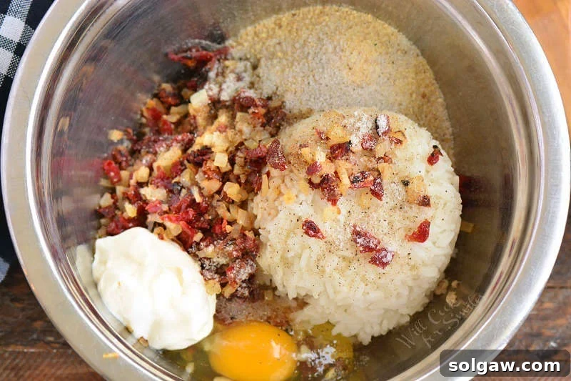 Savory Salmon and Rice Cakes 5 All the prepped ingredients, including sautéed onions and sun-dried tomatoes, flaked salmon, cooked rice, egg, and seasonings, gathered together in a large mixing bowl, ready to be combined.
