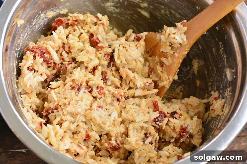 Savory Salmon and Rice Cakes 6 All the prepared ingredients for salmon and rice patties have been mixed thoroughly in a large bowl, showing a cohesive mixture ready for forming into patties.