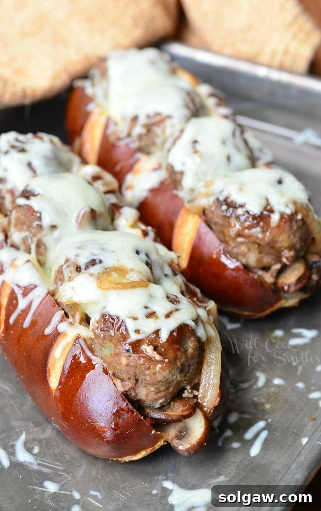 A finished Bacon Buffalo Meatball Sub on a pretzel roll, showcasing the rich melted mozzarella and juicy meatballs within.