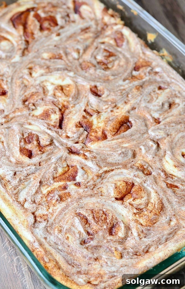 Top view of cheesecake Bars in a glass baking dish. There are swirls on top of the cheesecake where the cinnamon mixture has been swirled into the cheesecake mixture.