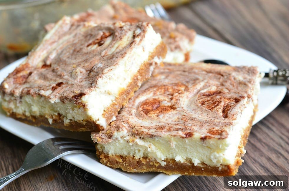 Several Caramel Cinnamon Swirl Cheesecake Bars lay piled on a small, white plate. A fork sets on the left rim of the plate.