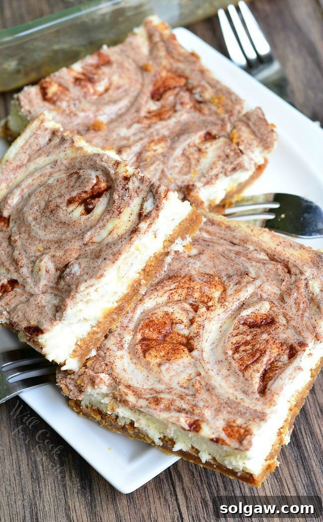 Several Caramel Cinnamon Swirl Cheesecake Bars lay piled on a small, white plate. Several forks also lay on the plate as well.