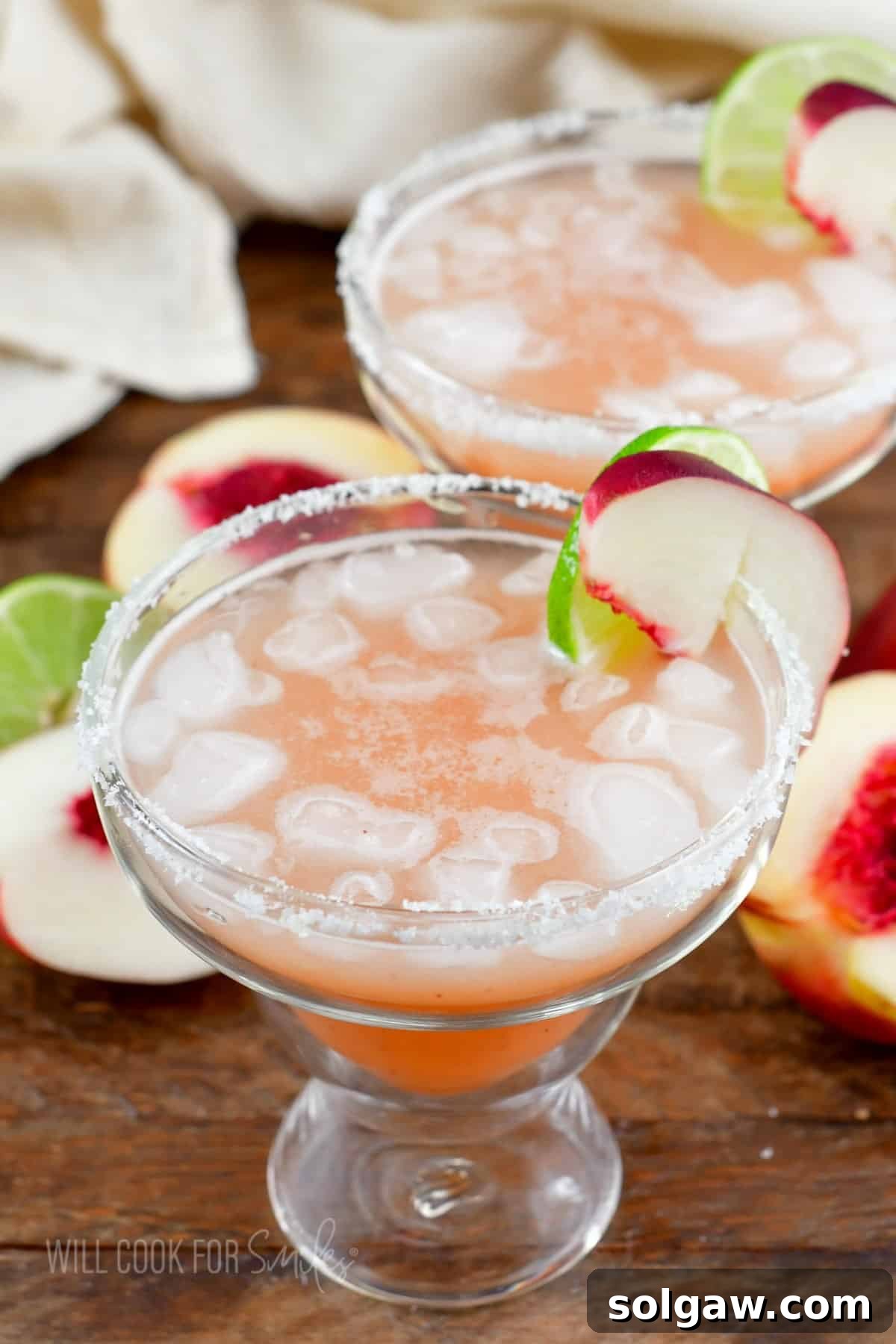 Two glasses, expertly rimmed with salt, are filled with vibrant peach margaritas, promising a delightful and refreshing drink.